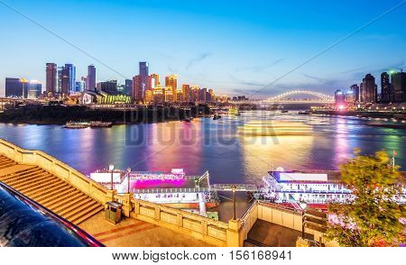 cityscape and skyline of downtown near water of chongqing at night