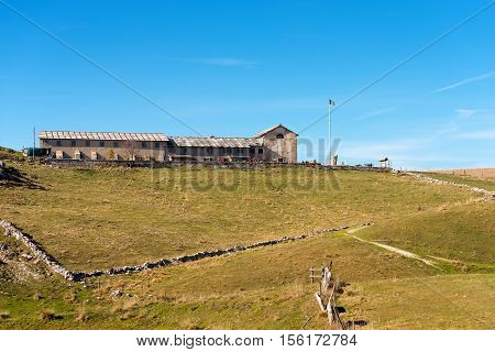 Typical old farm house (malga) for the breeding of cows with a small church. Plateau of Lessinia and Italian Alps Verona Veneto Italy
