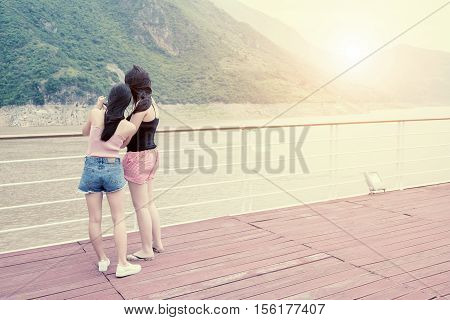 Two girls on the deck of the ship using a mobile phone camera