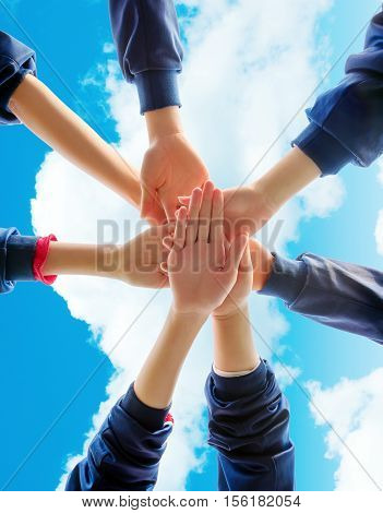Group of young people putting their hands on top of each other. Close up image of young students making a stack of hands.