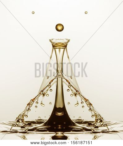 A mirror flipped image of a high speed flash water drop collision, coloured gold.