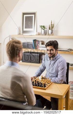 Two young men playing chess in room