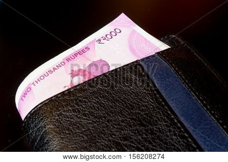 New Indian rupee 2000 note placed in a black leather wallet and isolated on black. The new currency has been introduced to curb black money