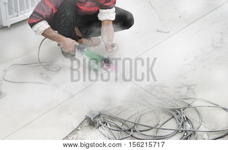 Man cutting concrete smooth with dust in floor