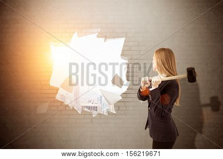 Woman is smashing wall with sledgehammer. Large city panorama is seen in the distancel. Concept of finding your way in business. Toned image