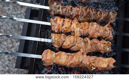 grilled meat over the coals on a barbecue. Skewered marinated chicken and pork. Uncooked marinated shish kebabs for grilling in BBQ