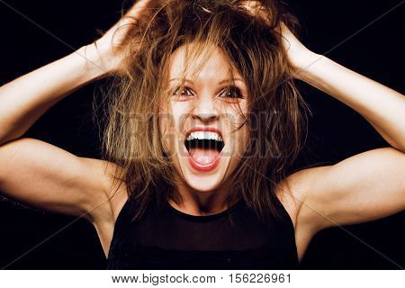young silly crazy girl with messed hair making stupid faces on black background, lifestyle people concept close up