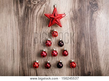 Red Christmas ornaments in the form of a Xmas tree on a rustic wooden background. Merry christmas card. Happy New Year. Top view with copy space