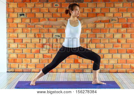 Woman practicing yoga in Class against a brick wall