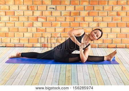 Beautiful Woman Practicing Yoga Doing Excercise Against A Brick Wall