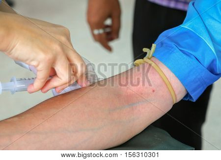 doctor injection needle selective focus syringe on arm to collect blood for test the health