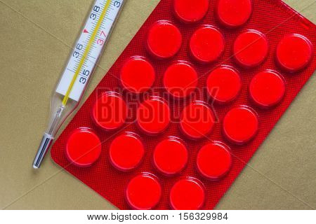 Medical thermometer and pack of pills. The cure for the flu.
