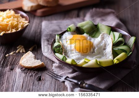 Traditional breakfast. Fried egg with sliced veetables, cheese and bread on old rustic table.