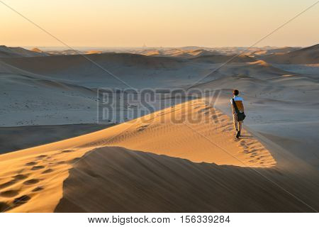Tourist Walking On The Scenic Dunes Of Sossusvlei, Namib Desert, Namib Naukluft National Park, Namib