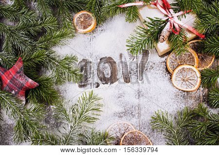 Christmas border composed of handmade christmas toys, fir branches, sliced oranges over a wooden background with space for text, overhead view. Christmas or new year card. Vintage. Rustic .