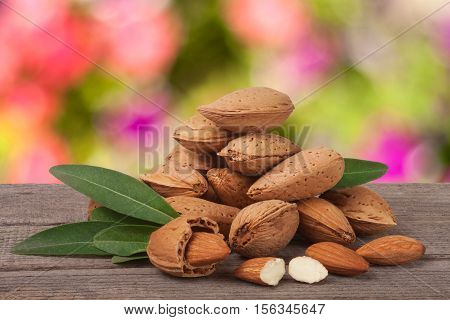 heap of almonds in their skins and peeled with leaf isolated on white background.