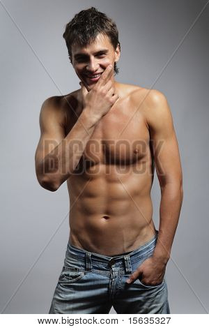 mladý muž pózuje na šedém pozadí