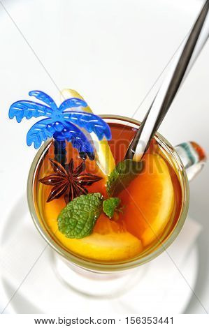 Grog in a glass mug decorated with orange slices and mint leaves.