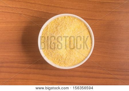 Corn Couscous into a bowl over a wooden table. Cuscus