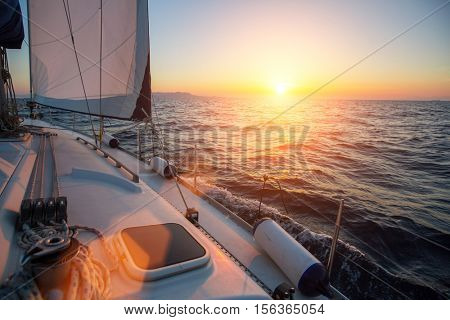 Amazing sunset at sea shot of a luxery yacht boat. Sailing in the wind through the waves.