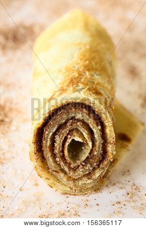Crepe roll filled with cinnamon and sugar photographed with natural light (Selective Focus Focus on the front of the roll)