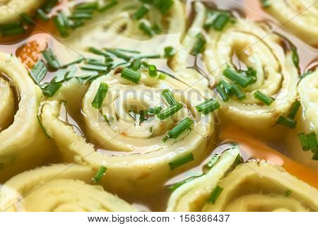 Traditional German Flaedlesuppe and Austrian Frittatensuppe based on consomme with rolls or stripes of pancake or crepe garnished with chives photographed with natural light (Selective Focus Focus in the middle of the image)