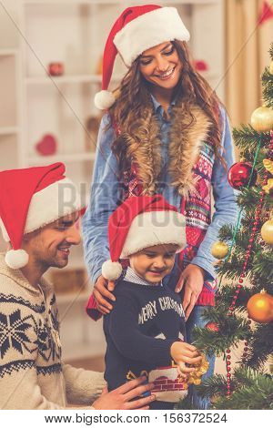 Happy young family decorating a christmas tree while celebrating Christmas at home