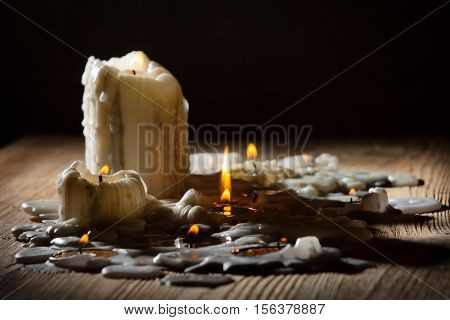 Candles with fire on wooden shelf on black background