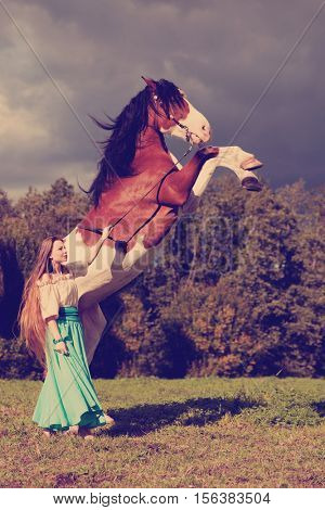 Beautiful young woman with a horse in the field. Girl on a farm with animal. Luxury woman outdoors
