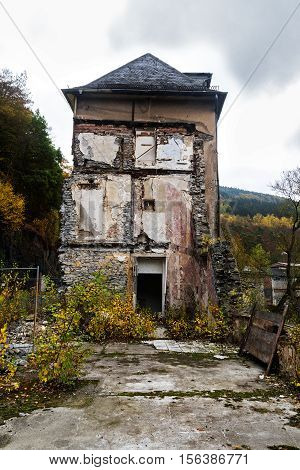 Decayed house half demolished in an autumn landscape metaphor for old age poverty or life evening without pension insurance selective focus