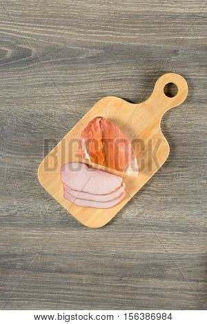 Appetizing bacon sliced on cutting board on wooden table