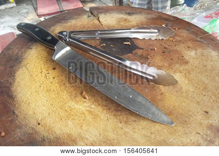 Long knife and ice tong on a dirty cutting board