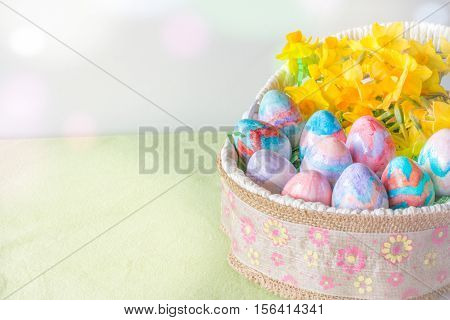 Basket of Hand Painted Easter Eggs with Daffodils on Table Horizontal with Copy Space Left & Bokeh