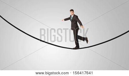A confident smiling salesman balancing on black wire in clear grey empty space concept