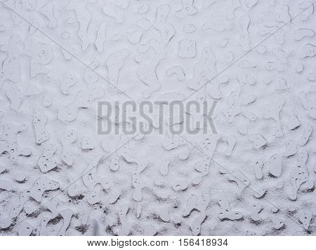 Texture of ice and drops on window glass in inclement winter weather. Close up. Icy rain background