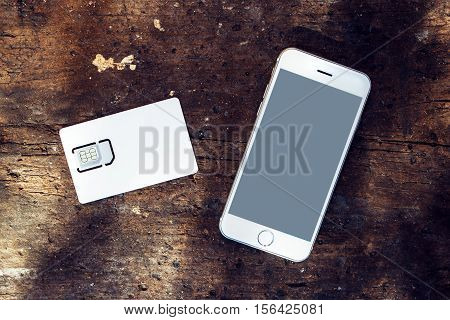 Smartphone with blank screen and mobile phone gsm SIM card on the table top view