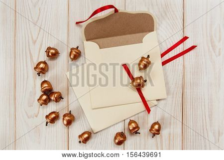 Christmas background.Envelopes with golden acorns.White wooden table.Mokup with empty space.Top view