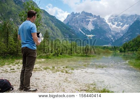Man controls drone with mountains on background. Alps, Italy