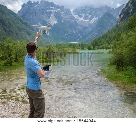 Man controls drone with mountains on background. Alps, Italy