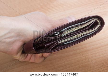 closed brown men's wallet with money in hand