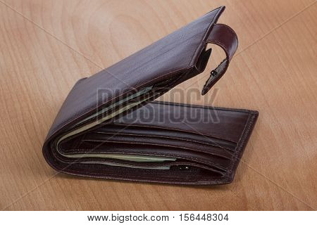 brown men's wallet with money on a wooden background