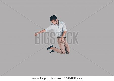 Man in mid-air. Mid-air shot of handsome young man jumping and gesturing against background