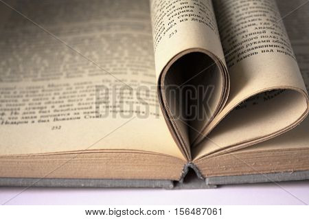 Heart shaped book pages. Old book page decorate to heart shape in vintage color tone. Composition of love with open book rolled in heart.