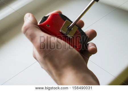 the young man unscrews the screw with a screwdriver