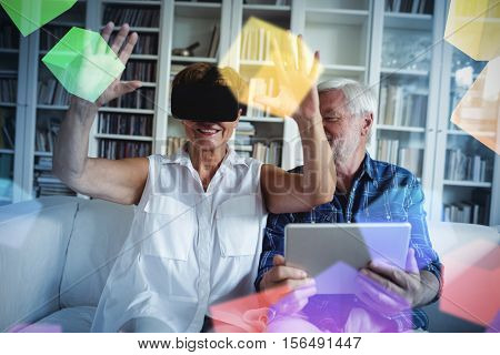 Digitally generated grey cubes floating against senior couple using digital tablet and virtual reality headset