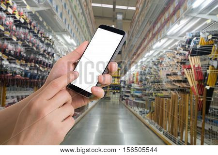 human hand hold smartphone tablet cell phone with blurry hardware store. concept of shopping and finding hardware tool for house repair.