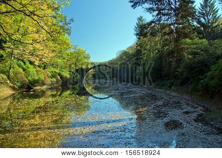 Arch Bridge in Kromlau, Saxony, Germany. Autumn in Park. Rakotz bridge in Kromlau