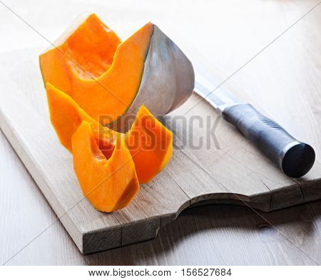 Sliced Pumpkin and knife on a wooden board.
