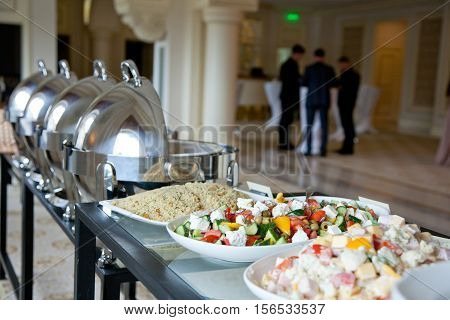 banquet table covered with salads and with businessmen in the background