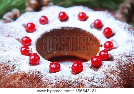 Christmas table setting. Bundt cake pudding sprinkled with sugar powder decorated with red currant.